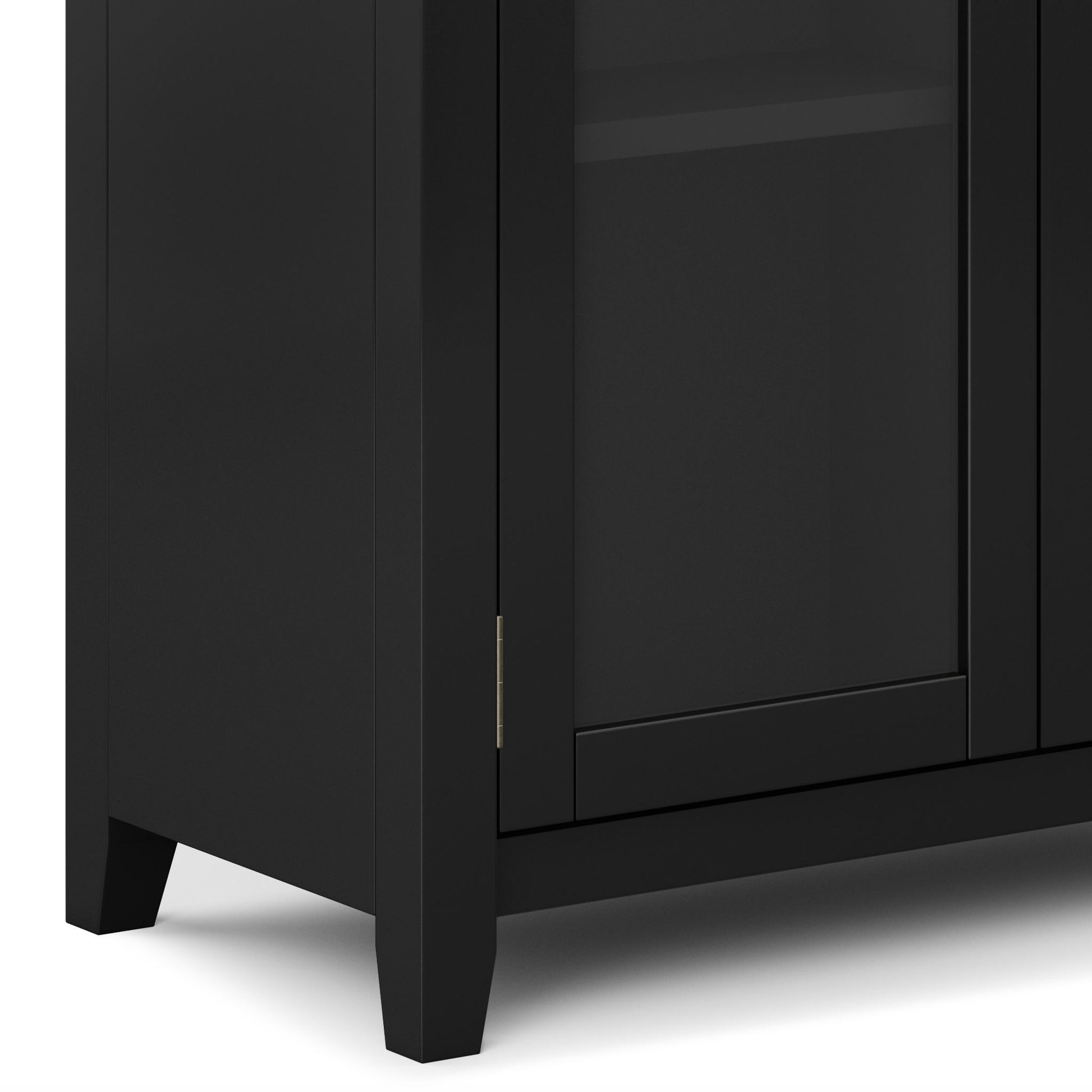 Close-up of the bottom corner of the Cosmopolitan - Handcrafted Medium Storage Cabinet in black, featuring a glass-panel door with visible hinge and short tapered legs.