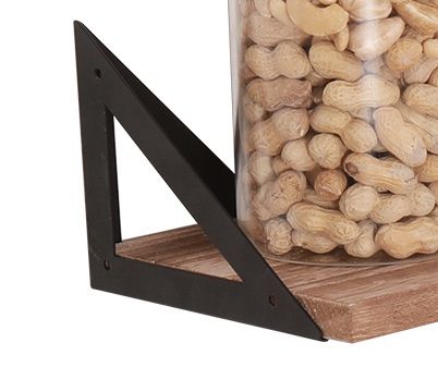 A close-up of a Floating Shelf from the Long Wall Shelves (Set of 3), featuring natural wood and a black metal bracket, holding a clear container filled with unshelled peanuts.