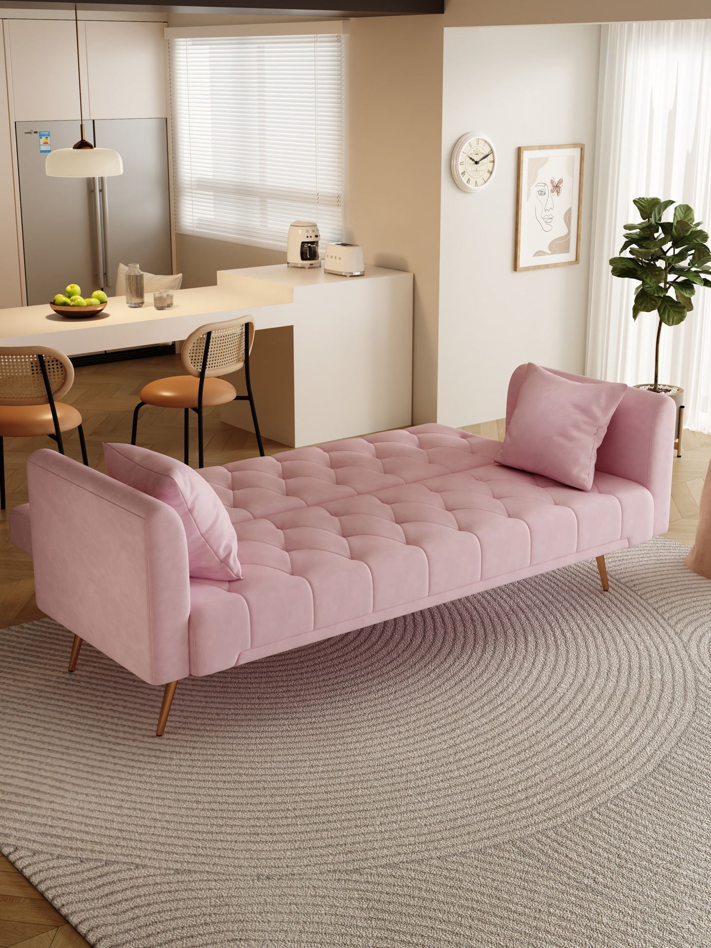 A modern living room showcases a Convertible Double Folding Living Room Sofa Bed in pink with two matching pillows on a round textured rug, set in front of a kitchen area with barstools, countertop, and minimalist decor.