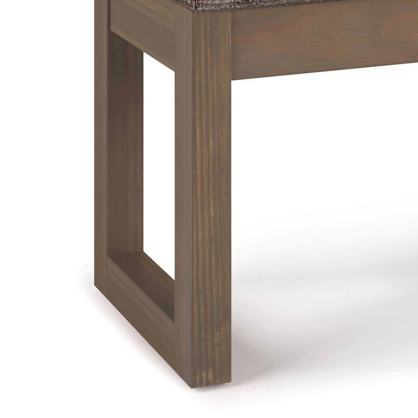 Close-up of the Milltown Upholstered Ottoman Bench shows a smooth, medium brown wooden frame with a rectangular open leg design and a cushioned seat, set against a plain white background.