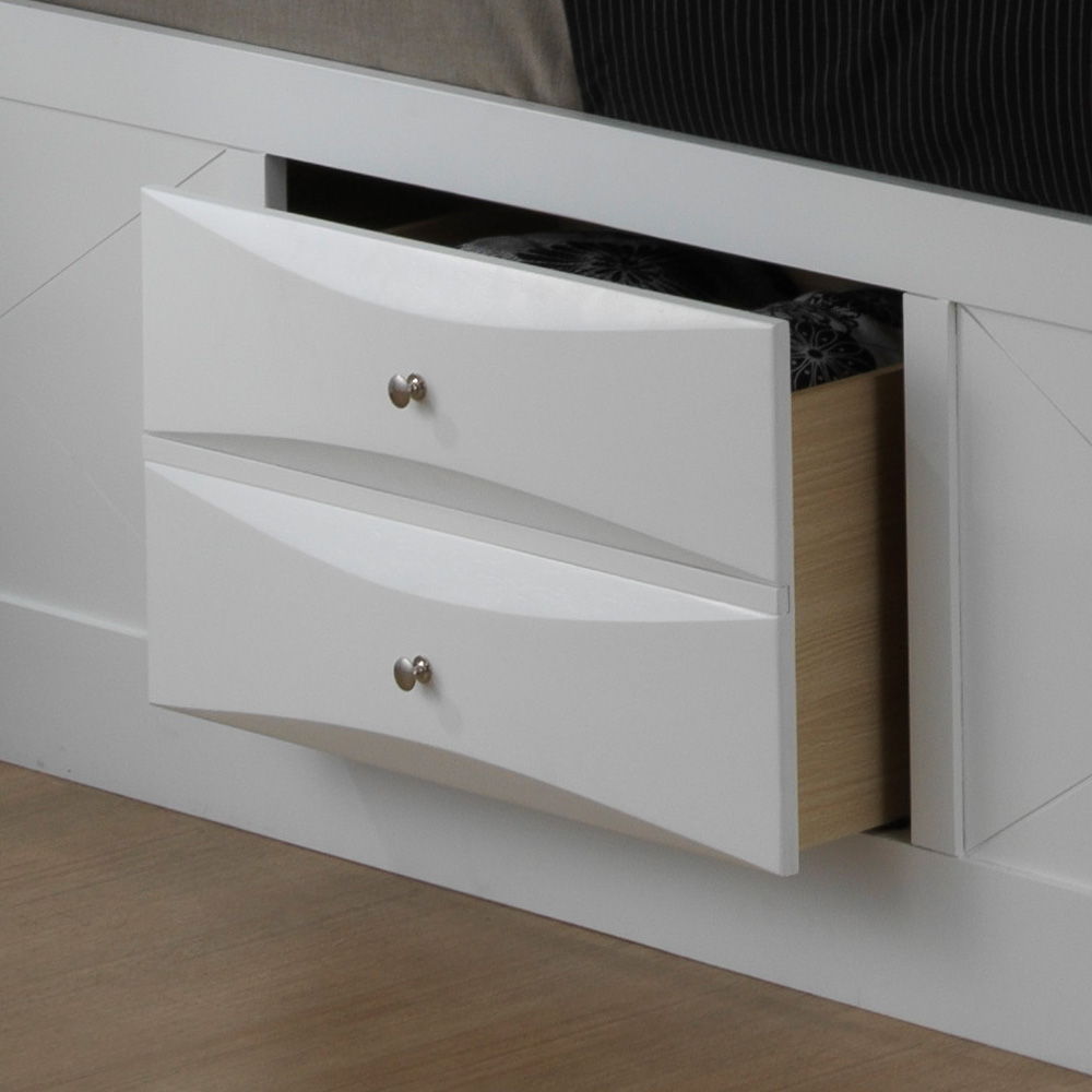 A close-up of the Marilla Storage Bed With Bookcase Headboard shows two partially open drawers with curved fronts and round metal knobs, revealing storage space inside. The bed frame and floor are wooden.