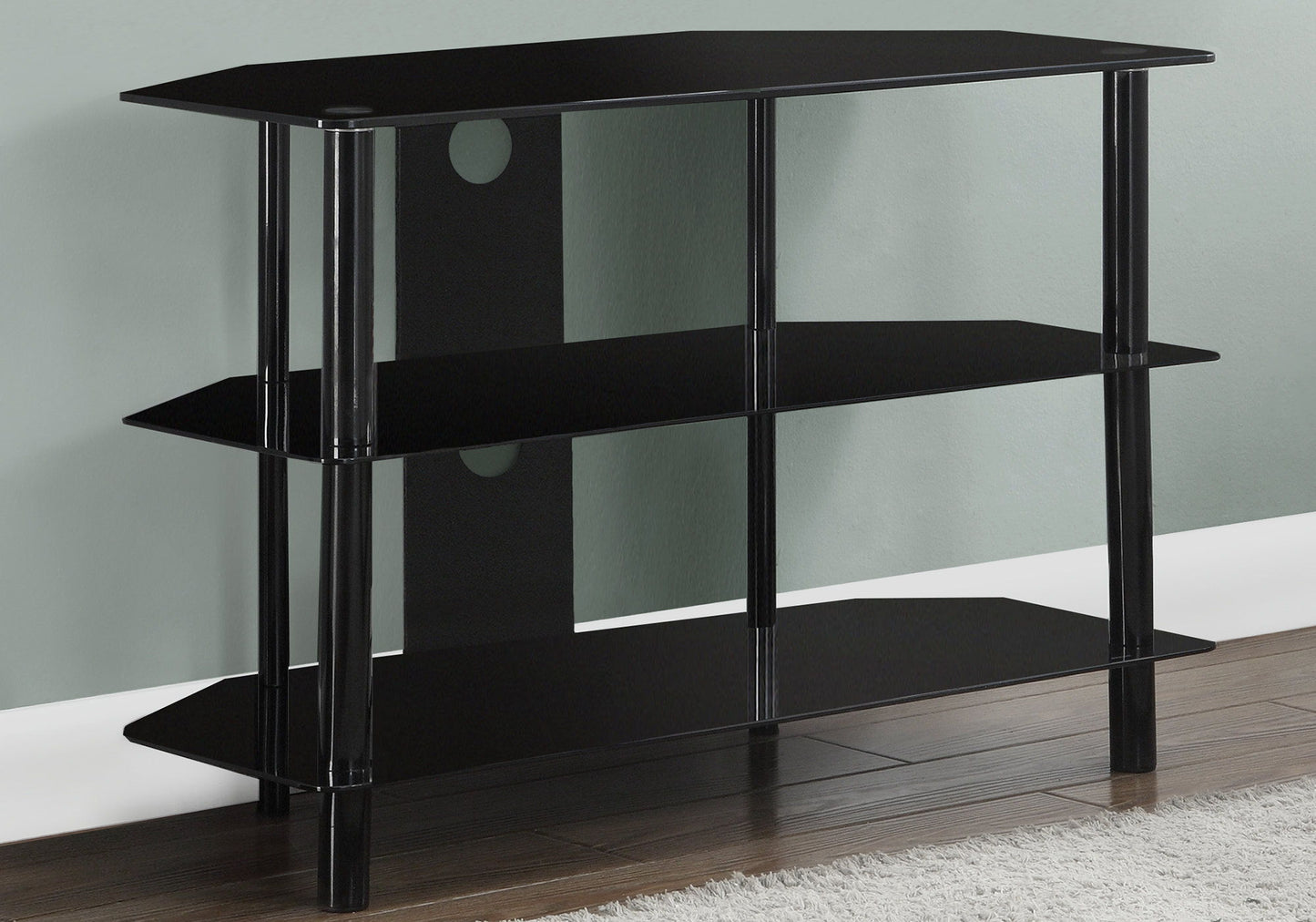 A black, 36-inch TV Stand Console with storage shelves and modern design, placed in a corner on a wooden floor by a white rug and against a light green wall.