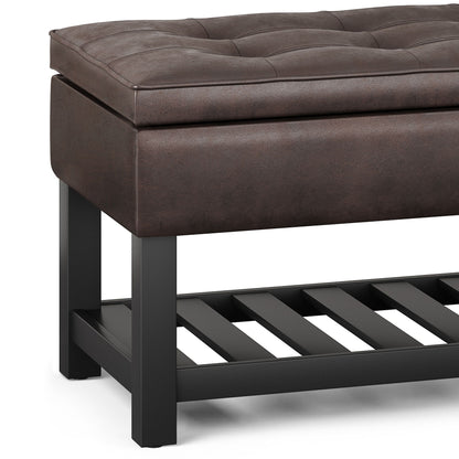 A close-up of the Cosmopolitan Storage Ottoman Bench with a brown tufted cushion, black wooden legs, and an open slatted lower shelf.