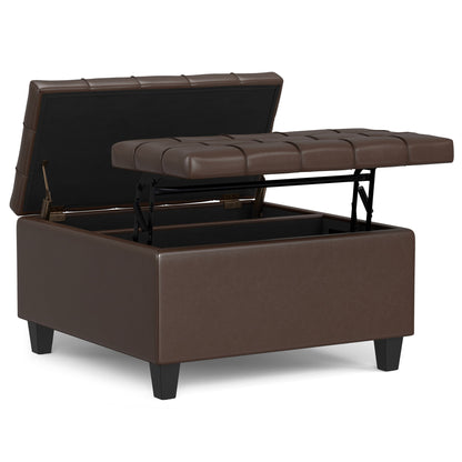 The Harrison - Large Coffee Table Storage Ottoman is brown and square with a tufted, cushioned lid that's partially open, showing an empty interior. It stands on four short black legs.