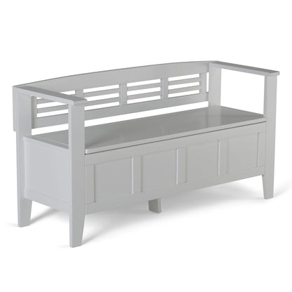 The Adams - Entryway Storage Bench Handcrafted features a white wooden frame, slatted backrest, open armrests, a paneled front design, and a storage compartment beneath the seat.