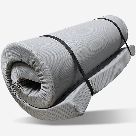 The Memory Foam Camping Mattress Foldable in gray is shown rolled up, secured with two black straps, against a plain white background. Portable and water resistant, it’s ideal for camping or travel.