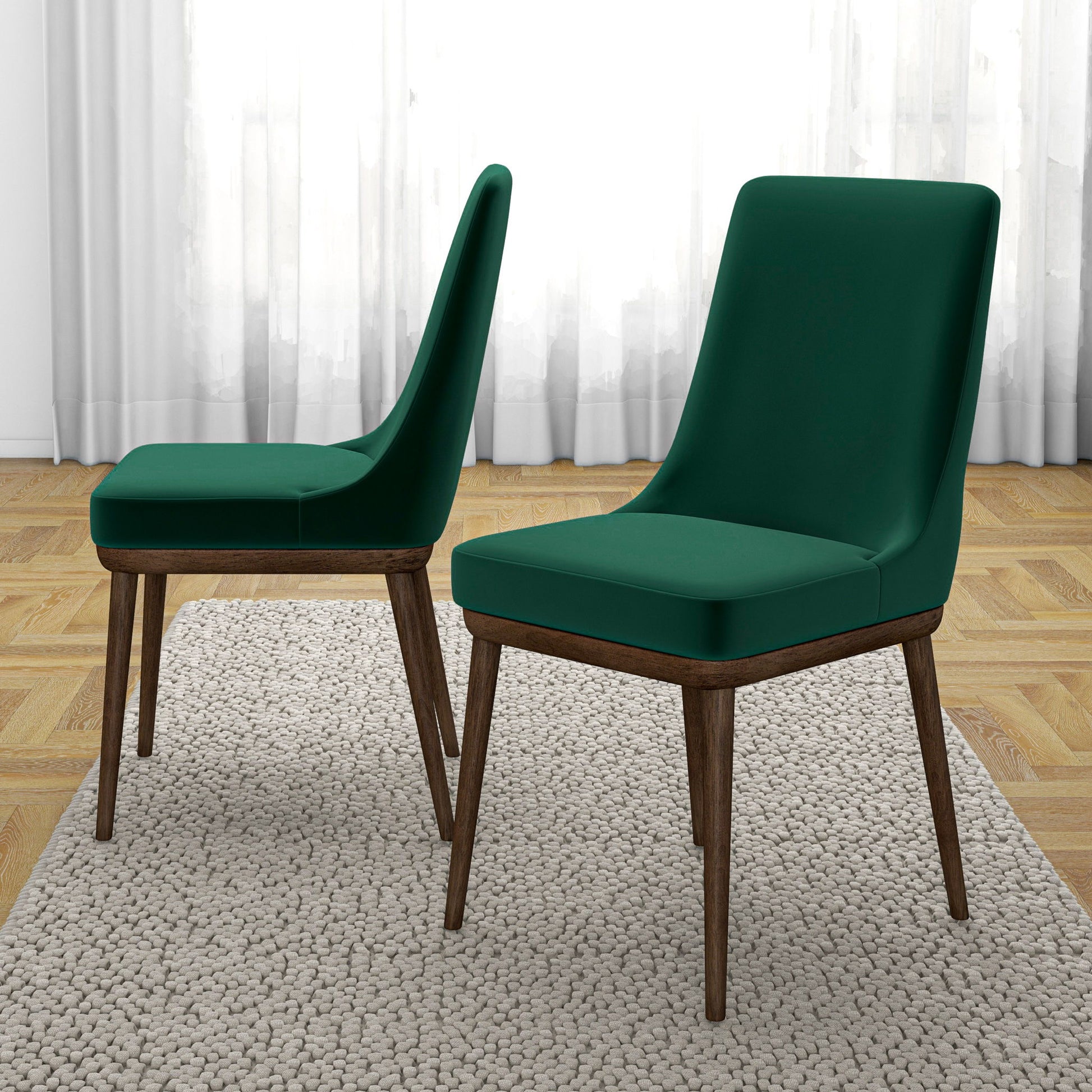 A set of two Kate Mid-Century Modern Dining Chairs with dark green cushions and wooden legs sit on a beige rug—one faces forward, the other in profile—in a room with wooden floors and white curtains.