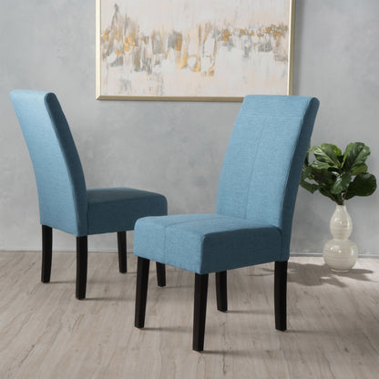 Two Pertica Dining Upholstered Armless Chairs (set of 2) with blue fabric and black legs sit on a light wood floor. A green potted plant in a white vase and an abstract painting decorate the light gray wall in the background.