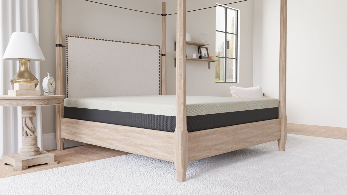 A modern bedroom with a light wood four-poster bed, an 8" Comfort Series Firm Gel Memory Foam Tight Top Mattress in black and white, a round wooden side table with a lamp and clock, wall shelf, window, and a white rug on a light floor.