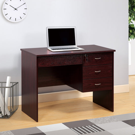 A mahogany student desk with three locking drawers on metal glides and metal bar handles stands against a light gray wall, topped with a laptop. Nearby are a clock, trash bin with rolled papers, and a patterned rug on the wooden floor.