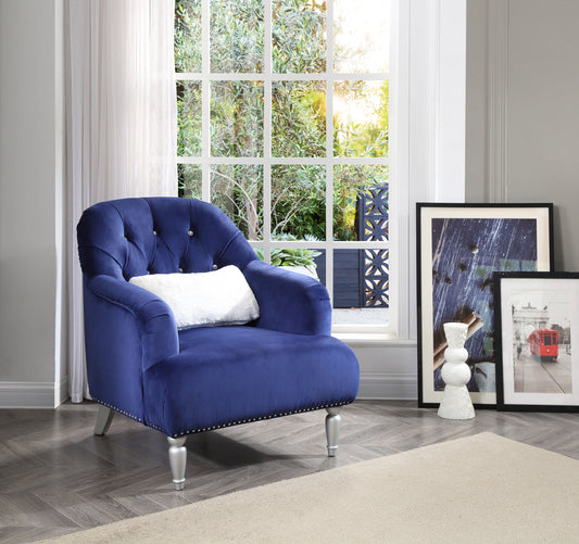 The Jewel - Chair - Blue with a white pillow rests on a wooden floor by a large window. A framed red tram poster and a white decorative sculpture sit nearby as sunlight filters through the trees outside.