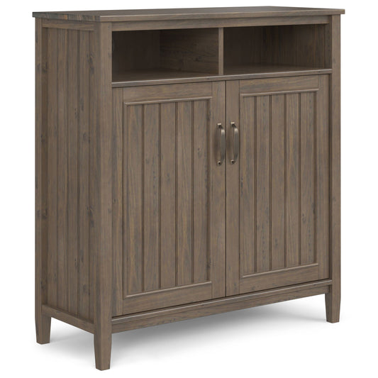 The Lev Medium Storage Cabinet in Smoky Brown features two vertical panel doors with metal handles, two open shelves above, stands on four legs, and showcases a rustic farmhouse style with its weathered wood finish.