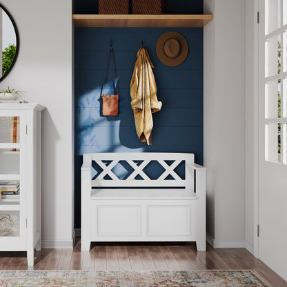 The Amherst - Small Transitional Entryway Storage Bench sits against a blue shiplap wall in a bright entryway. Above, hooks hold accessories, while two baskets are on a shelf nearby as sunlight casts soft shadows.