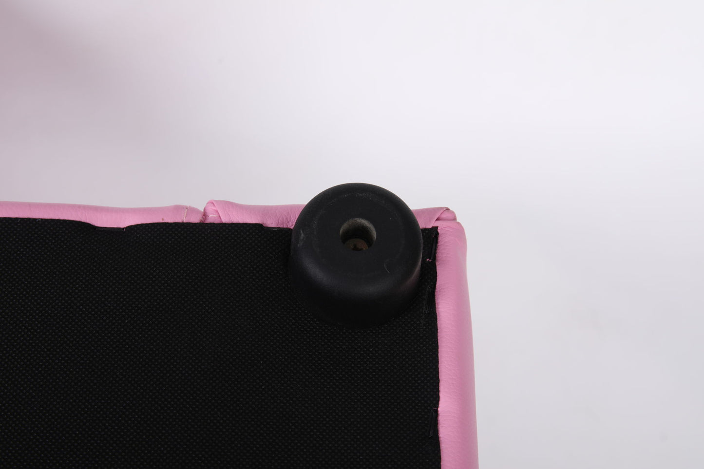Close-up of the corner of the Kids Club Chair Sofa / Sectional And Ottoman - Pink, showing black plastic or rubber foot attached to pink and black fabric upholstery against a white background.