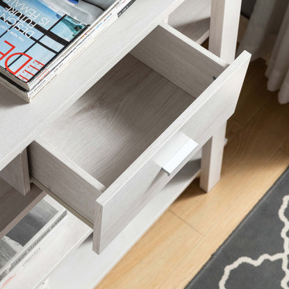 The Modern Home Display Cabinet 4 Tier Open Shelving With Center Drawer in White Oak features an open drawer, magazines on top, a shelf below, and sits on a wood floor beside a patterned dark gray rug.