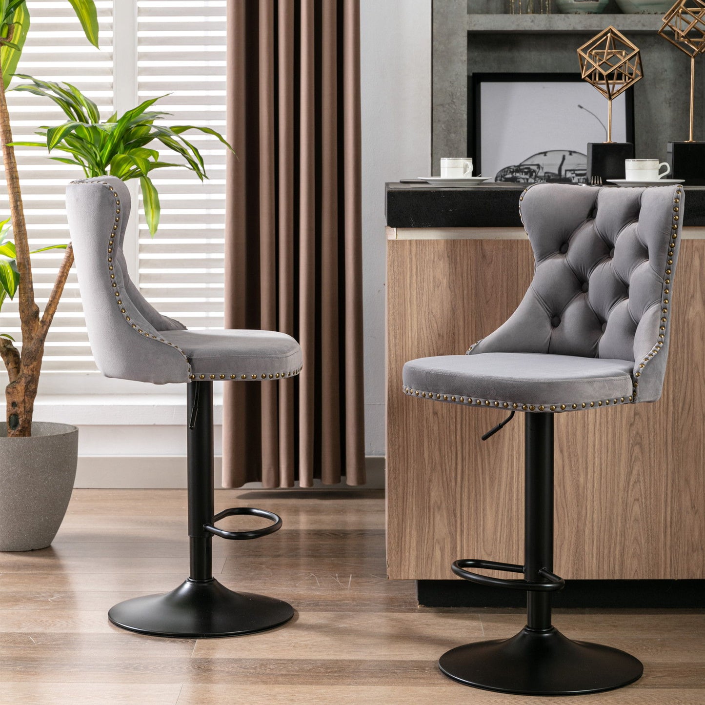 A set of two Swivel Velvet Barstools with tufted backs stands on black metal bases in a stylish room with wood floors, a potted plant, and neutral curtains. These modern upholstered stools feature adjustable seat height for home or kitchen island use.