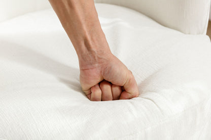 A person presses their clenched fist into the soft, white chenille fabric cushion of the Swivel Accent Barrel Chair, creating an indentation in the seat.