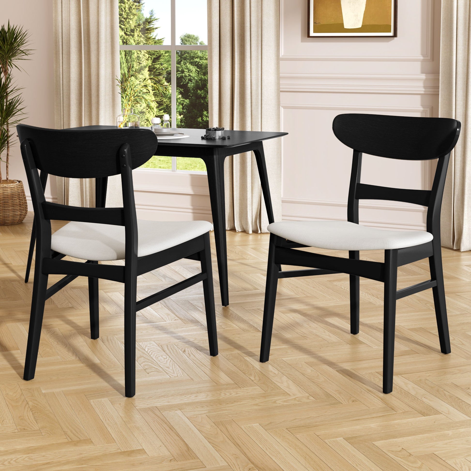 Two Mid Century Dining Chairs with cushioned seats and wood frames are placed near a small black dining table in a bright room with herringbone floors, beige curtains, a large window, and framed wall art.