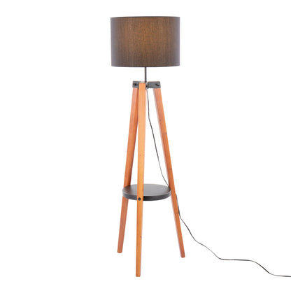 The Compass Mid Century Modern Floor Lamp features a brown cylindrical shade, three wooden tripod legs, a round black shelf midway, and a visible black power cord.