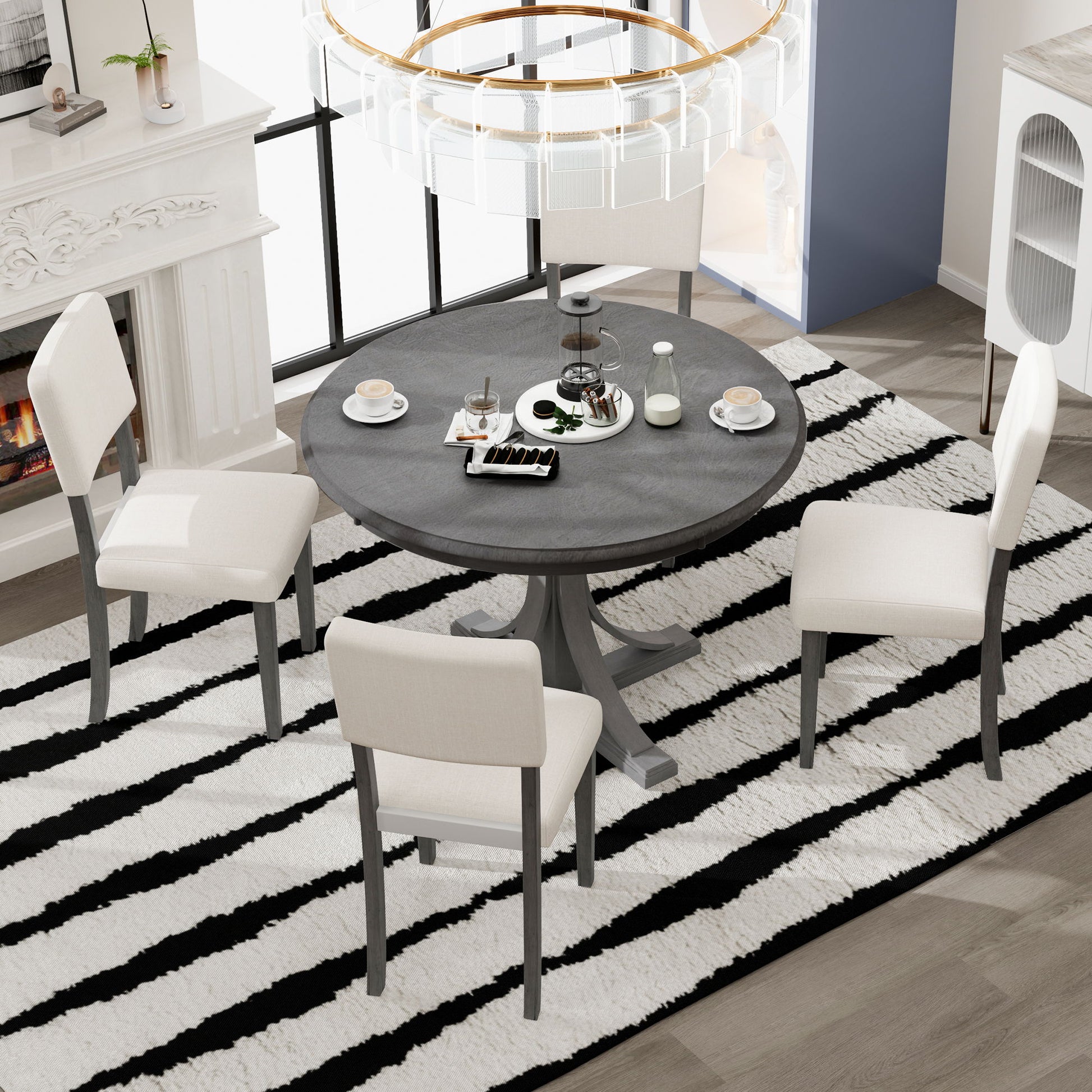 The bright room features the Retro Round Dining Table Set with curved trestle legs and upholstered chairs on a black-and-white striped rug. The table is set with coffee cups, plates, desserts, and a teapot, near a white fireplace and modern chandelier.