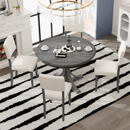 The bright room features the Retro Round Dining Table Set with curved trestle legs and upholstered chairs on a black-and-white striped rug. The table is set with coffee cups, plates, desserts, and a teapot, near a white fireplace and modern chandelier.