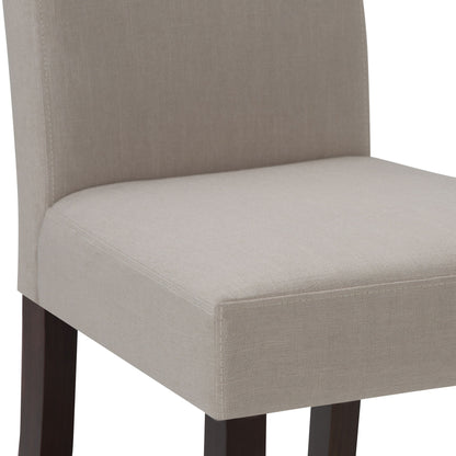 Close-up of the Acadian - Upholstered Parson Dining Chair (Set of 2), showing its light beige upholstered seat and lower backrest with dark wooden legs. Only the seat and lower backrest are visible.