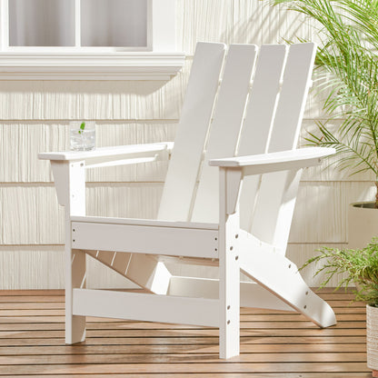 An Enigmara Outdoor High Density Resin Adirondack Chair sits on a wooden deck by potted plants, with a clear glass of water on the armrest and sunlight casting shadows across the chair and wall.