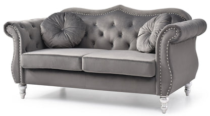 The Stylish Flared Arm Loveseat features gray tufted velvet upholstery, silver studs, rolled arms, two round matching pillows, and white turned wooden legs.