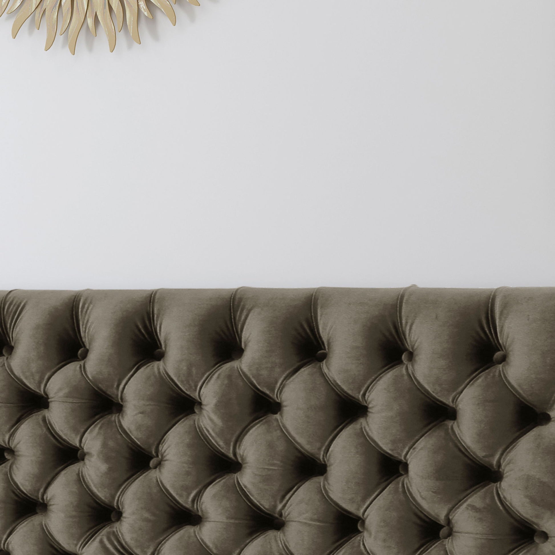 The Annecy - Contemporary Upholstered Headboard in dark gray stands against a white wall, with a decorative gold sunburst mirror partially visible in the upper left corner.