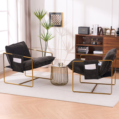 Two Upholstered Hanging Armchairs with gold-plated frames, crushed foam cushions, and skin-friendly woven fabric face each other across a round coffee table on a beige rug. A wooden bookshelf, potted plant, and chessboard accent the bright room.
