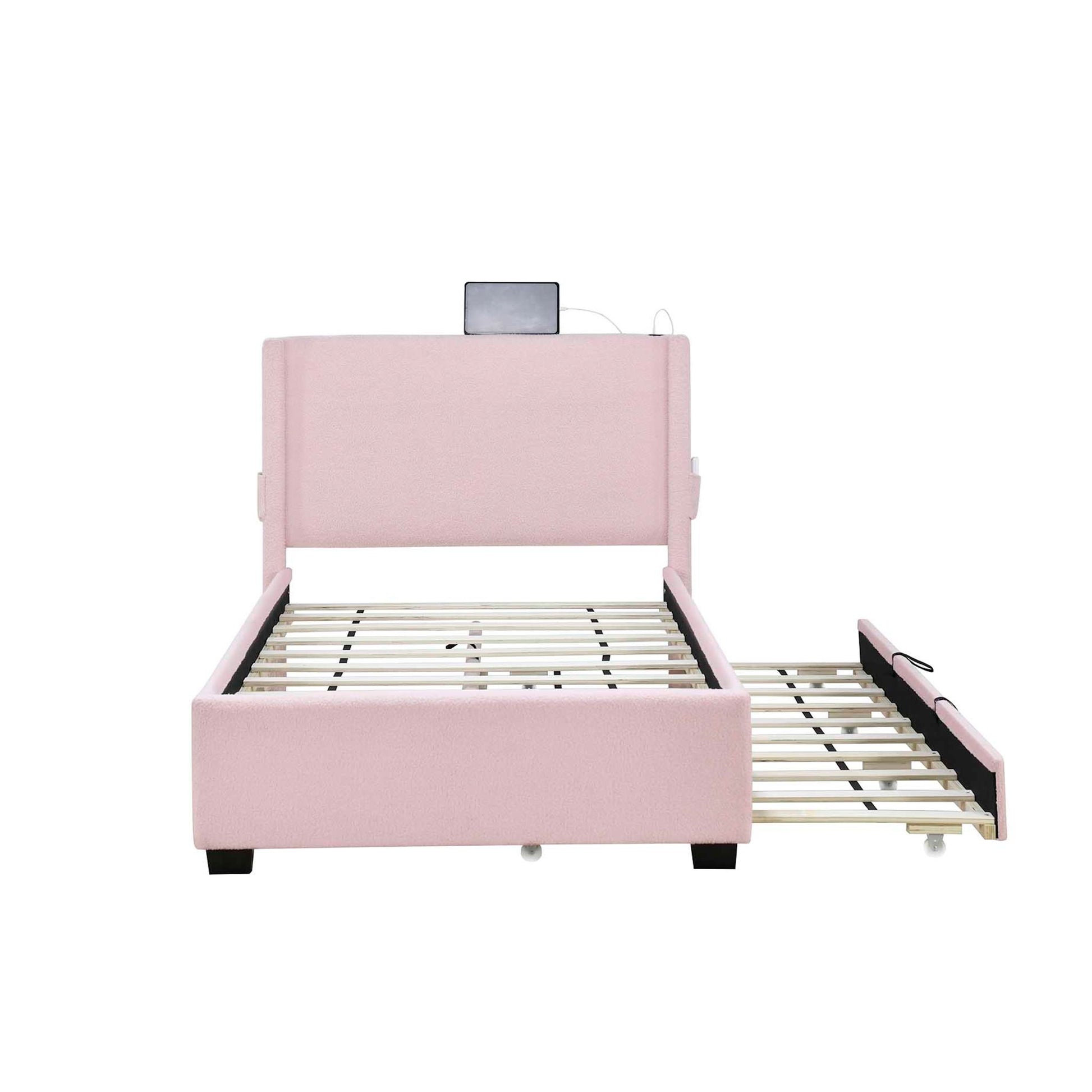 A baby pink twin size upholstered bed frame with a teddy fabric finish, featuring a pull-out trundle bed, USB functionality, and a side pocket on the headboard for storing small items.