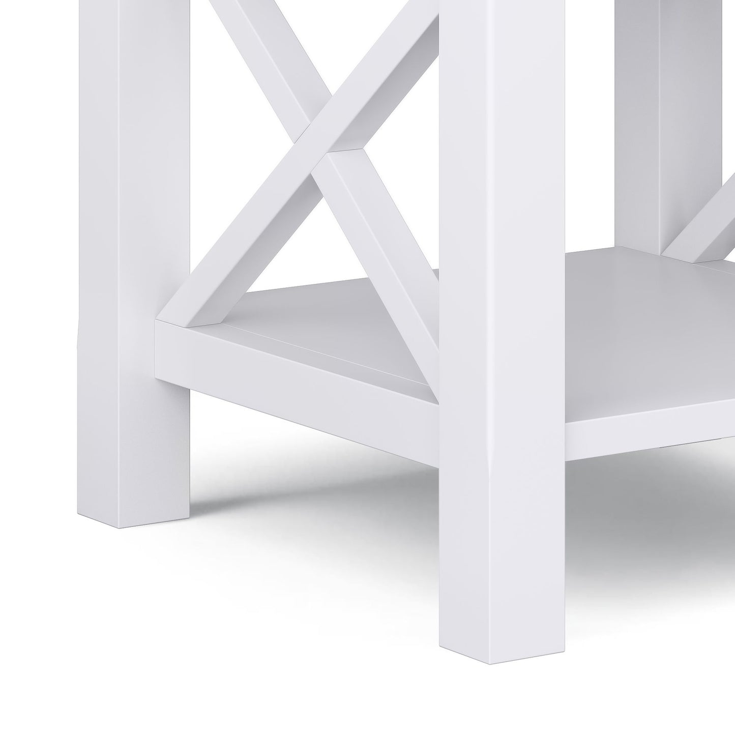 Close-up of the lower corner of the Kitchener - Handcrafted Table, showcasing its white wooden build, X-shaped side supports, and a flat bottom shelf.