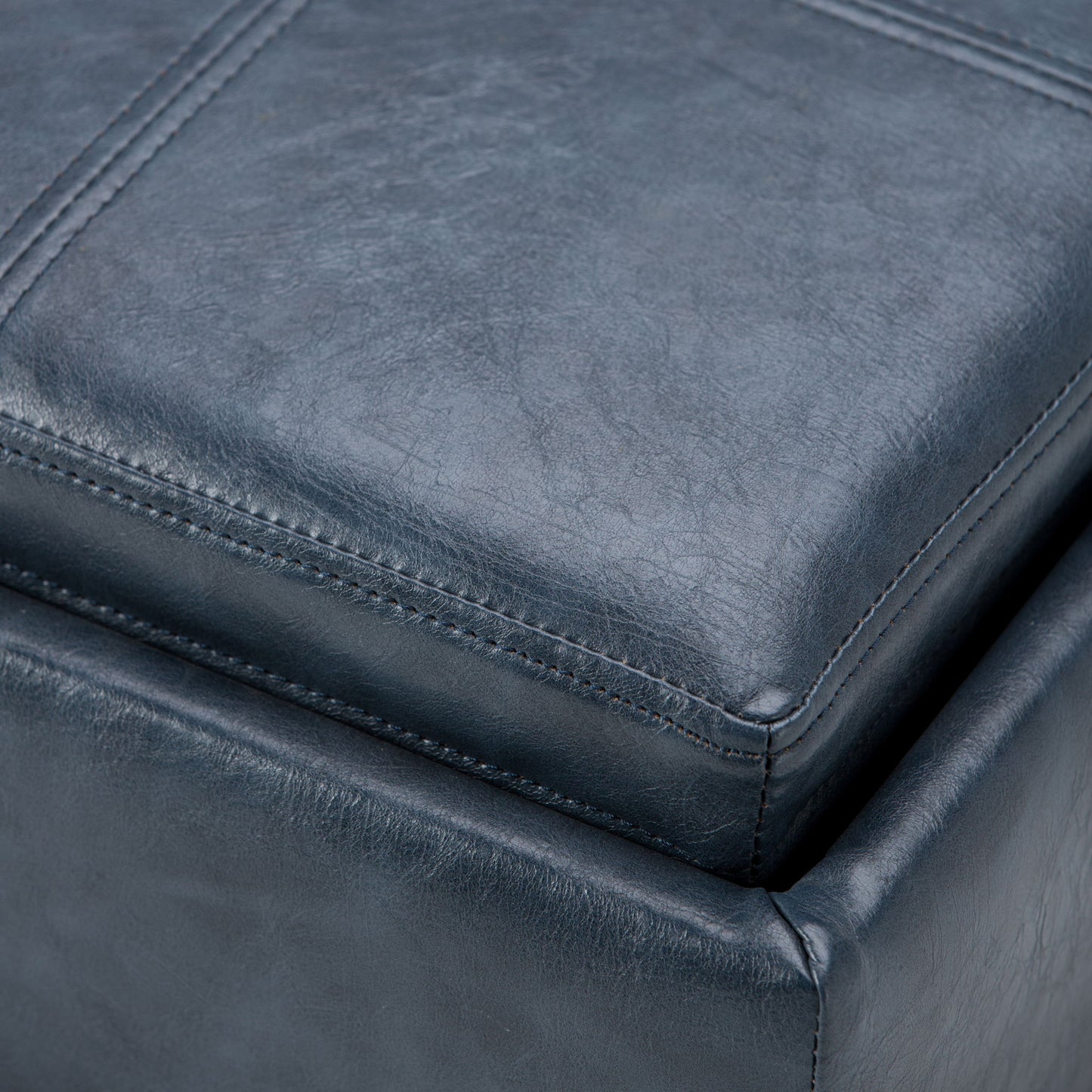 Close-up of the Rockwood - Upholstered Cube Storage Ottoman With Tray in dark blue leather, highlighting its detailed stitching and soft, textured surface.