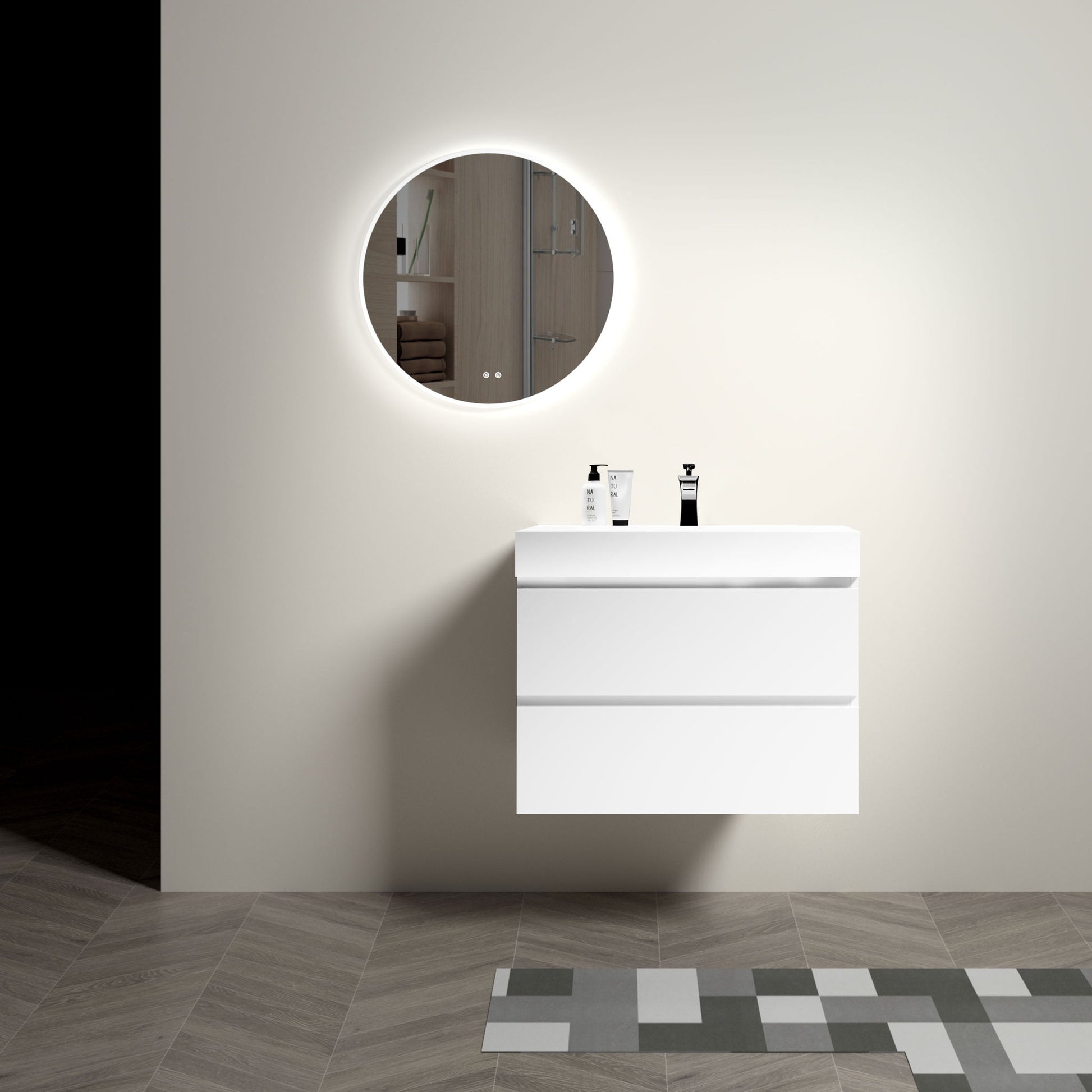 A minimalist bathroom features the Alice Wall Mounted Floating Vanity with a large storage and one-piece sink, paired with a round backlit mirror, two bottles on the counter, and geometric tile flooring against a light wall.