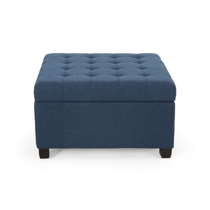 The Isabella Contemporary Ottoman With Storage features a square, dark blue tufted design and short black legs, displayed against a white background.