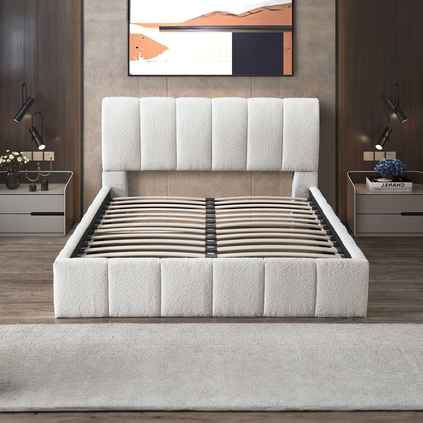 A modern bedroom showcases the Hilar - Elegant Design Platform Bed in white upholstery (shown without a mattress), complemented by matching nightstands, lamps, flowers, books, and abstract art above a wood-paneled wall.
