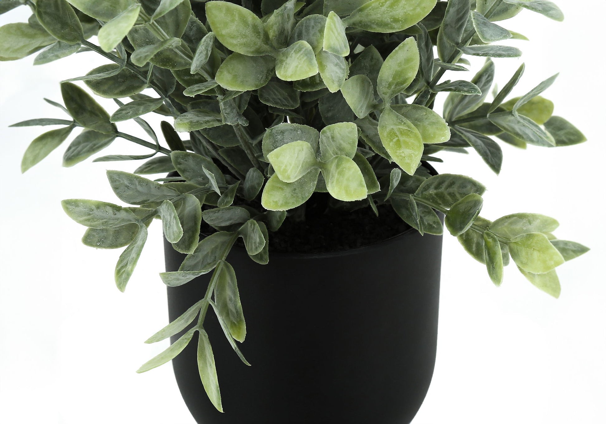 A close-up of the 11" tall artificial eucalyptus grass plant, featuring dense green foliage in a matte black pot, set against a white background. This decorative indoor faux greenery comes as a set of 2.