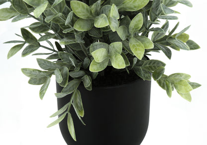 A close-up of the 11" tall artificial eucalyptus grass plant, featuring dense green foliage in a matte black pot, set against a white background. This decorative indoor faux greenery comes as a set of 2.