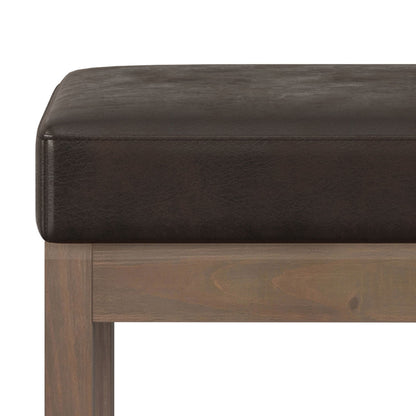 Close-up of the Milltown - Upholstered Ottoman Bench featuring a thick, dark brown leather cushion on a light wood frame, set against a white background.