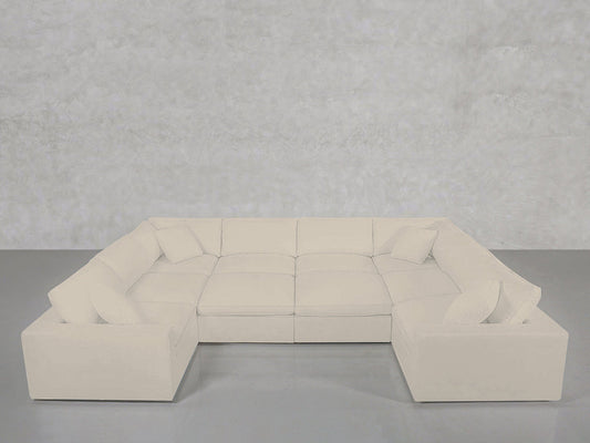 A spacious, light cream 10-Seat Modular Closed Pit sectional with plush cushions and matching throw pillows, arranged against a plain light grey wall and floor.