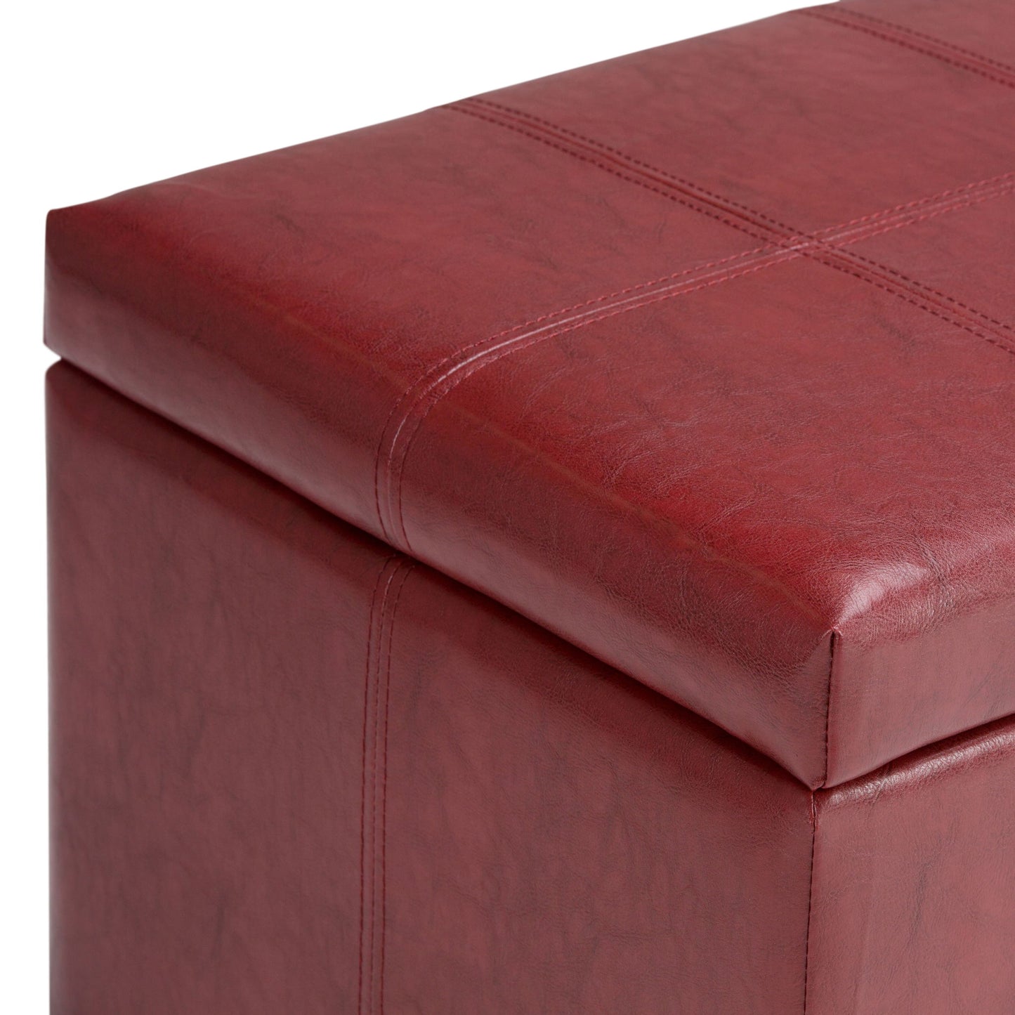 Close-up of the corner of the Dover Upholstered Storage Ottoman Bench in red faux leather, showcasing visible stitching and a slightly textured surface.