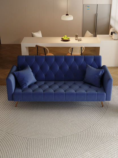 A modern living space features a Convertible Double Folding Living Room Sofa Bed in blue with two matching cushions on a circular rug. In the background are a dining table with chairs, green apples in a bowl, and a refrigerator.