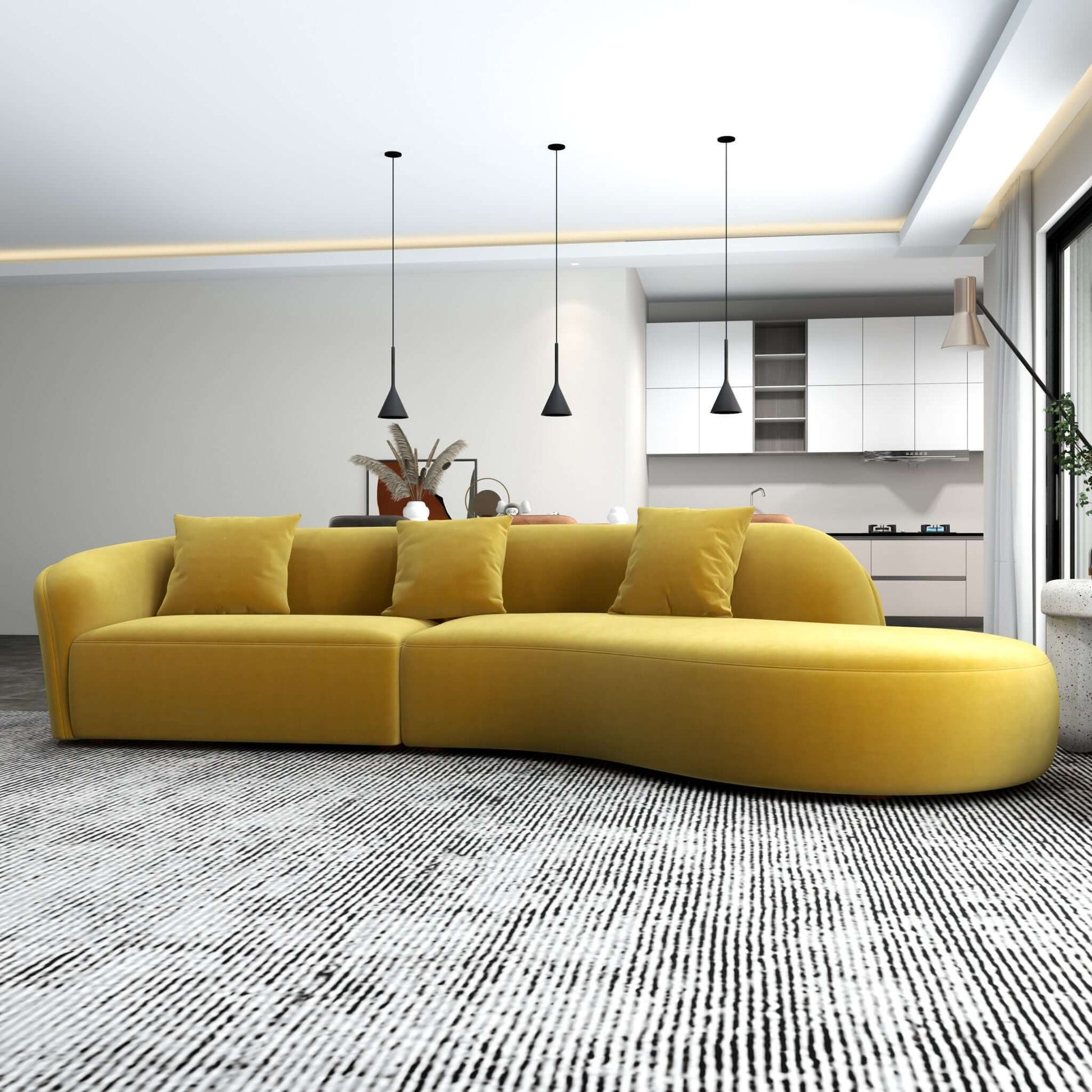 A modern living room features the Elijah - Japandi Style Curvy Sectional Sofa with matching cushions on a black and white patterned rug. Three pendant lights hang near an open kitchen with white cabinets and a dining table, all bathed in natural light from large windows.