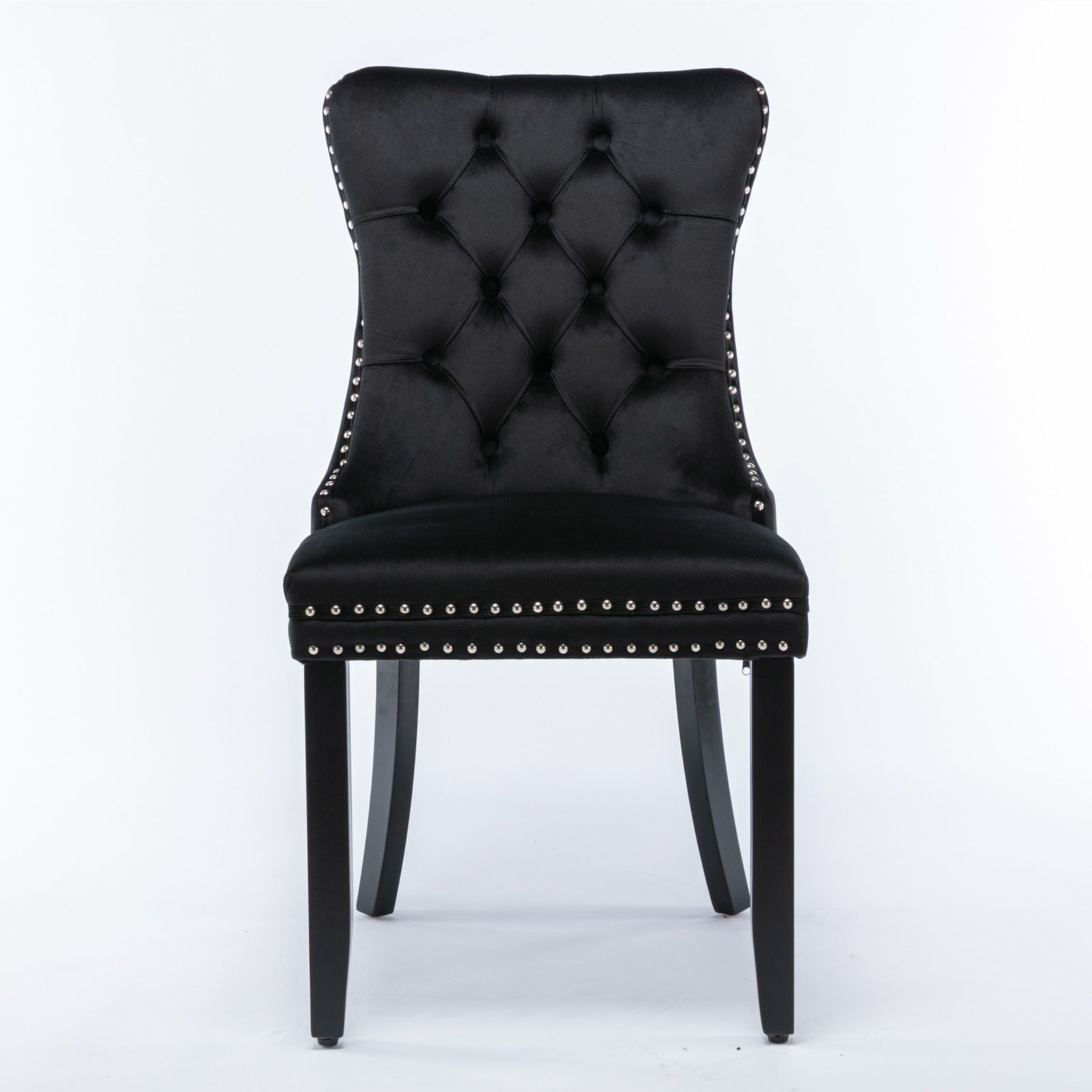 The Nikki is a modern black velvet dining chair with a high, curved, button-tufted back, silver nailhead trim, and four black solid wood legs. Set of 2 contemporary upholstered chairs.