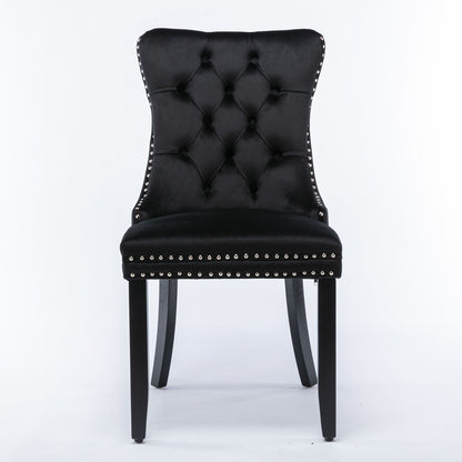 The Nikki is a modern black velvet dining chair with a high, curved, button-tufted back, silver nailhead trim, and four black solid wood legs. Set of 2 contemporary upholstered chairs.