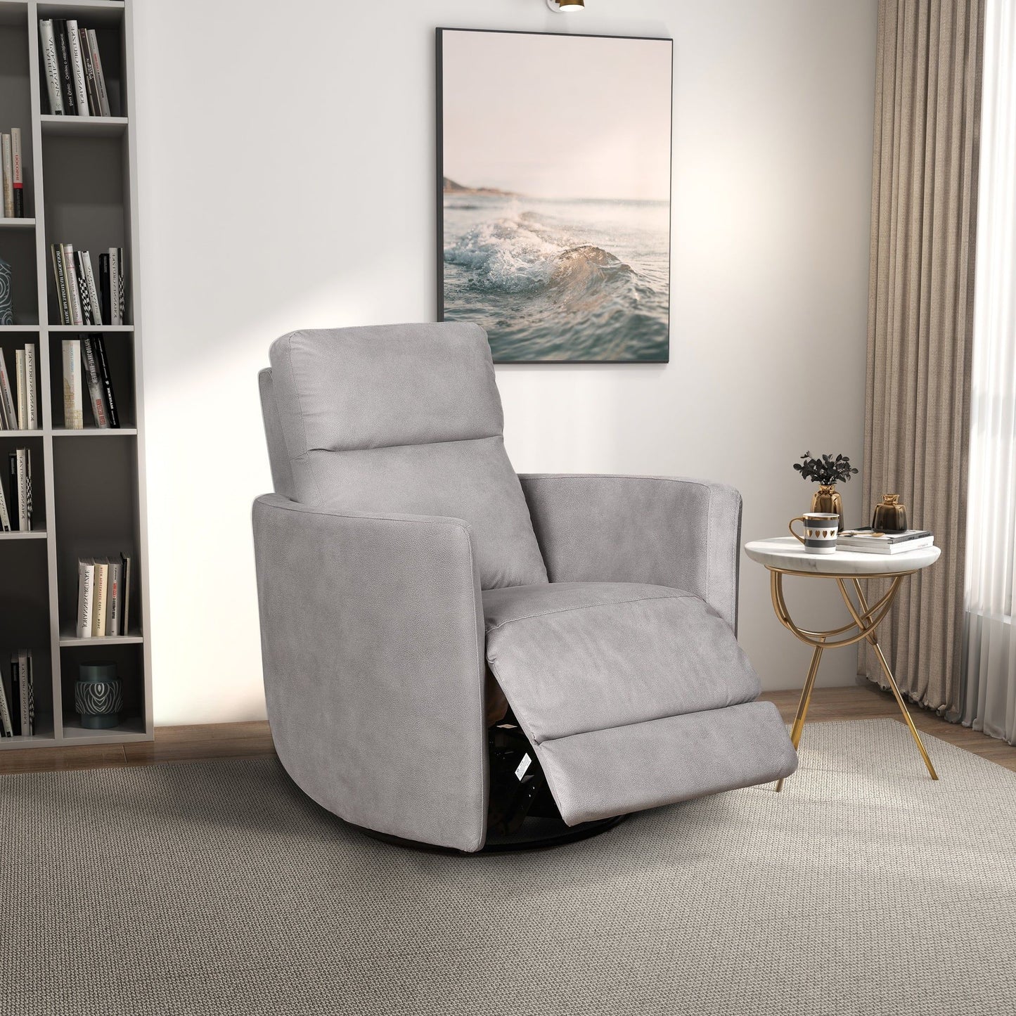 A modern living room featuring the Lawson Swivel Glider Suede Recliner Chair in Latte, a round white side table with gold legs, books, a small plant, bookshelf, large ocean artwork, and natural light streaming through sheer curtains.