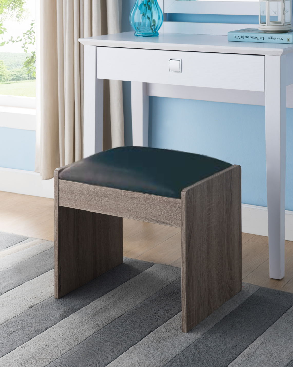 The Vanity Cushioned Stool Chair Dark Brown sits on a striped rug before a white desk in a bright room with light blue walls and beige-curtained window.