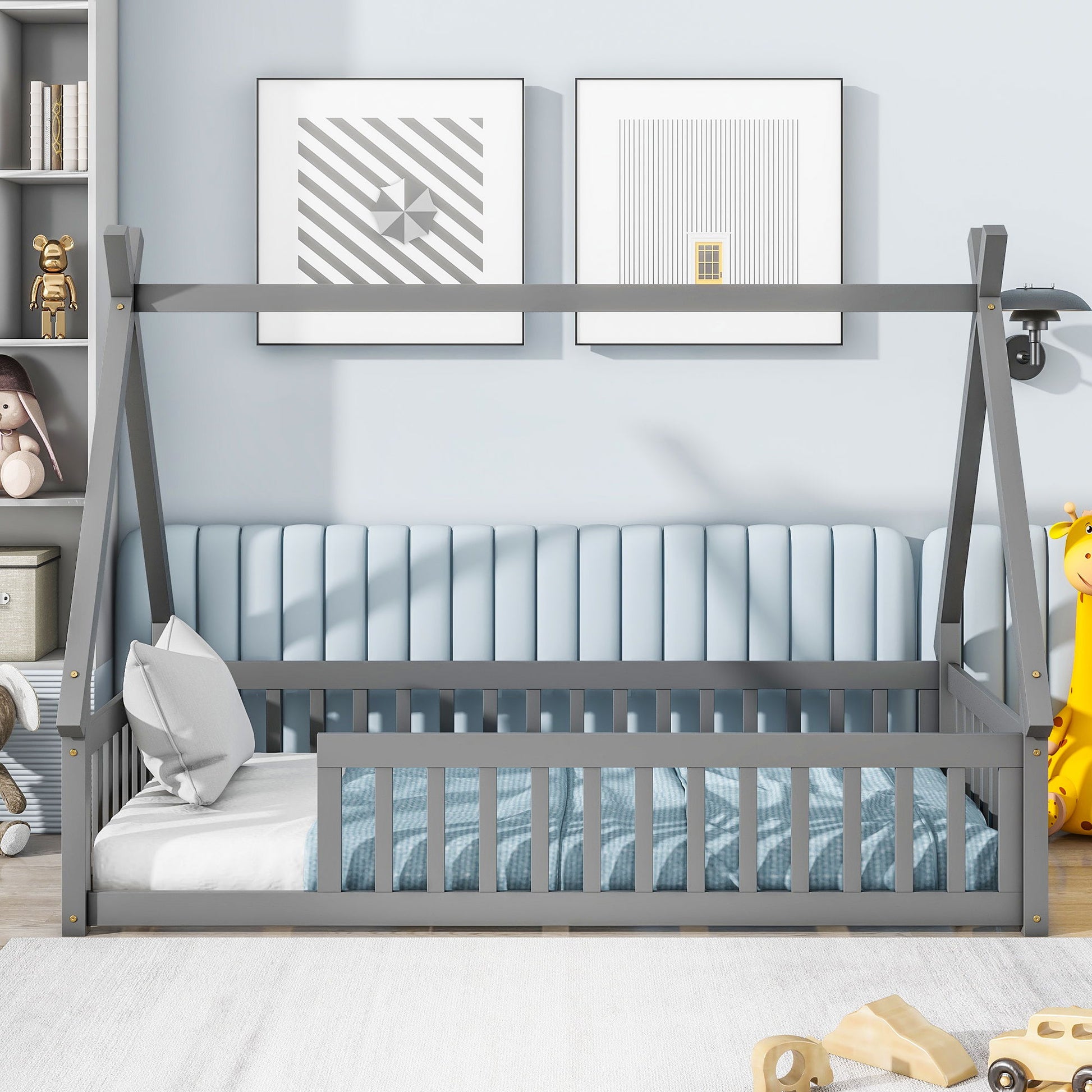 Tent-Shaped Floor Bed with guardrails and slats in a modern, light blue nursery. The bed features striped bedding and pillows, complemented by stuffed toys, framed geometric art, and a cushioned wall panel.