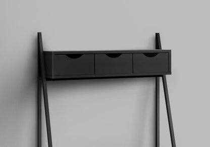 A contemporary black computer desk for home office with storage drawers and angled legs, designed for laptops, leaning against a plain gray wall.