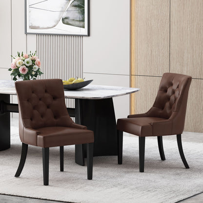Two Cheney Contemporary Dining Chairs with brown tufted upholstery and black legs sit beside a modern dining table with a white marble top, adorned with a vase of flowers, fruit bowl, and contemporary decor in the background.